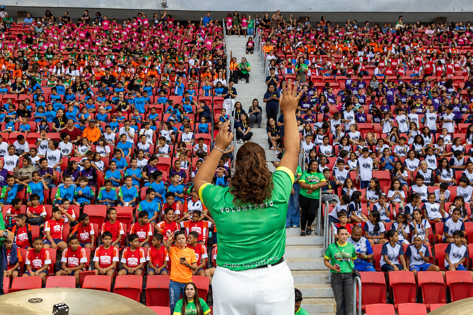 Voluntária celebrando com a arquibancada lotada de crianças
